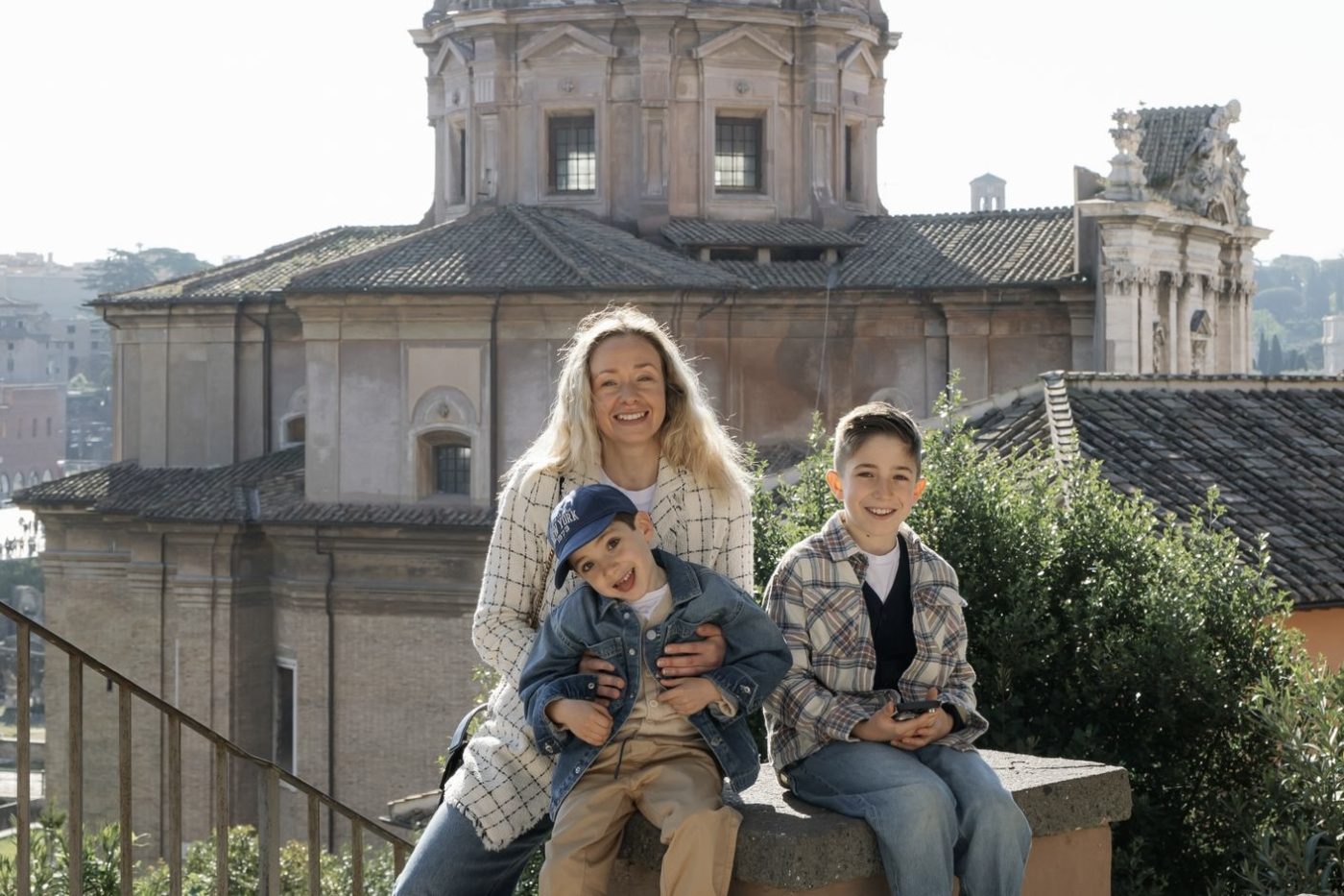 Mamma e due bambini in pausa su un parapetto durante il percorso nella Roma storica