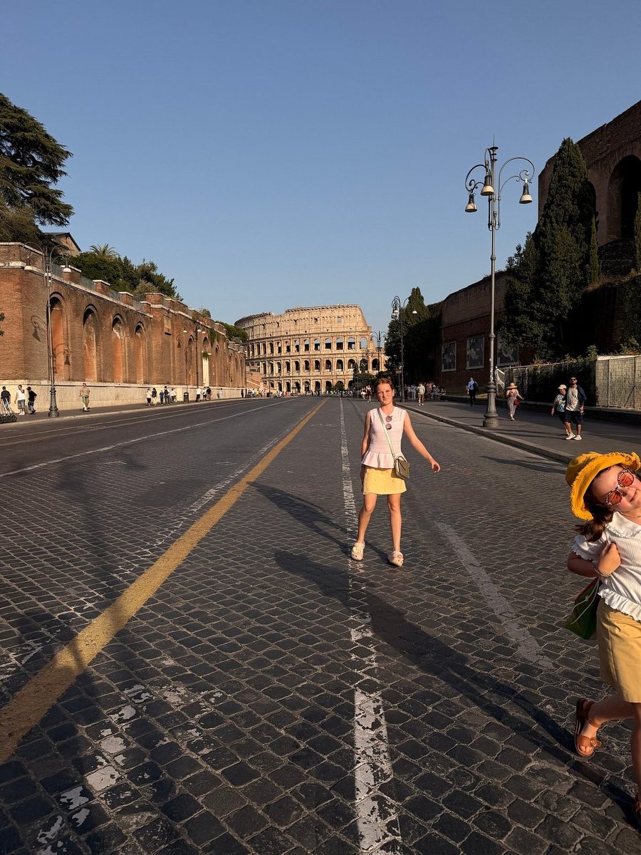 A girl runs down the street leading to the Colosseum