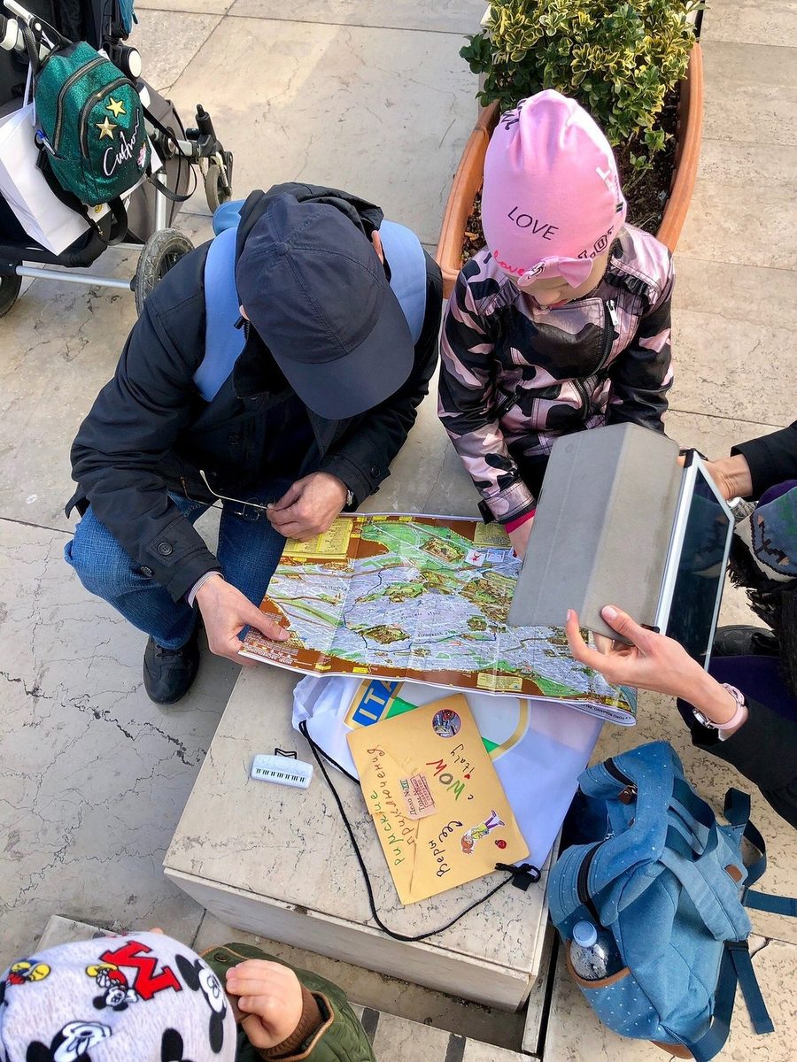 Adults and children bending over the quest map