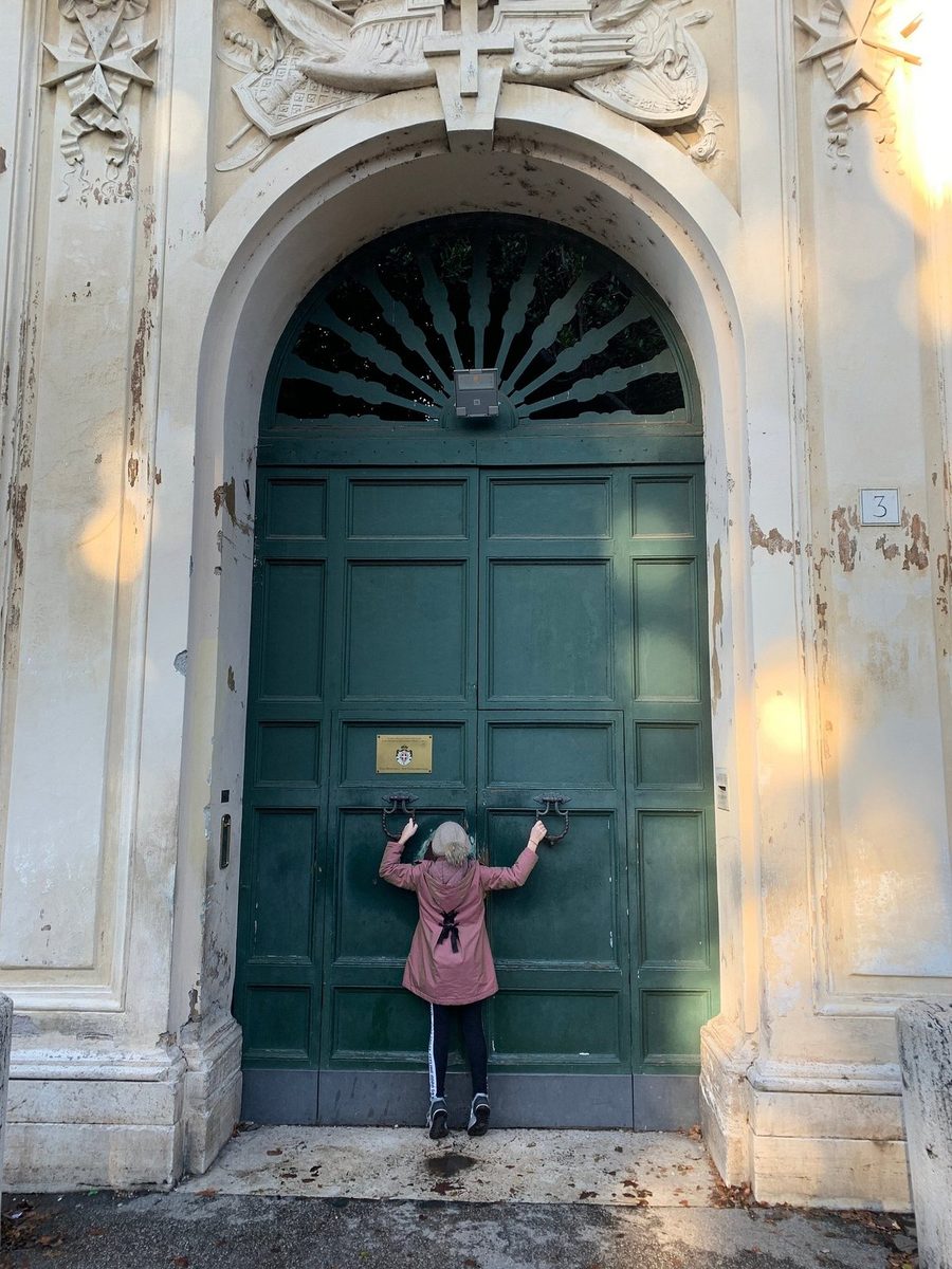 A child by a massive green door with a keyhole