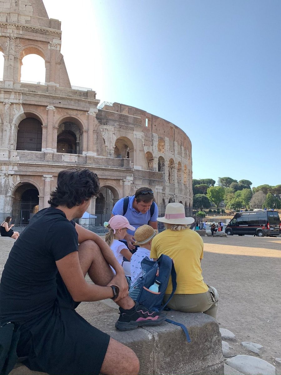 An adult and children work through a task on the stones by the Colosseum