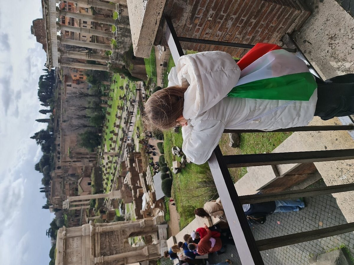 A child with an Italian flag at the railing above the Forum